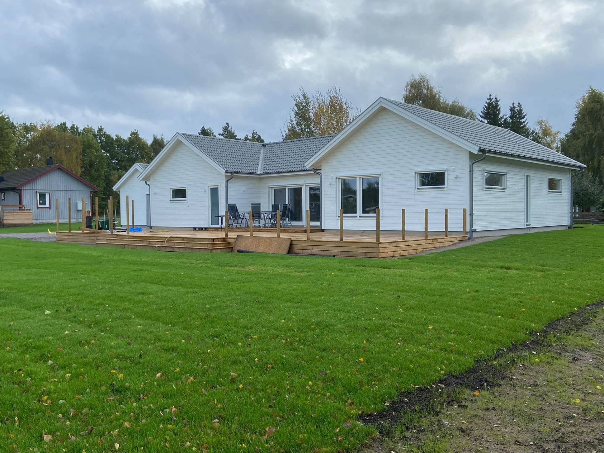 Nybyggd vit villa med trädäck och stor gräsmatta i Kalmartrakten